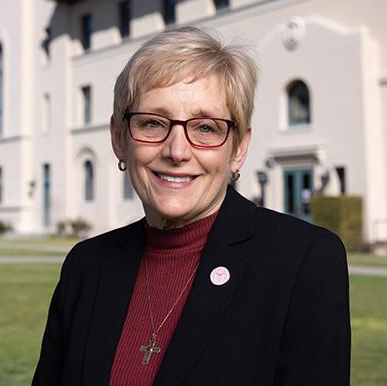 President Julie Sullivan standing on lawn outside of Mission Church with St. Joseph's Hall in the background.