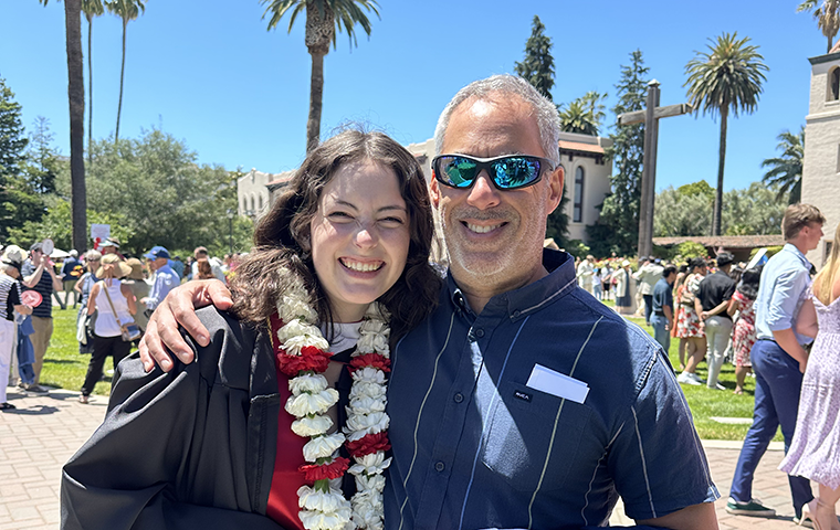 Man and daughter at Santa Clara commencement, standing outside Mission Church. 