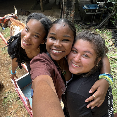 Juana Melgoza takes a selfie with two friends. In the background is a bull facing away from the camera.