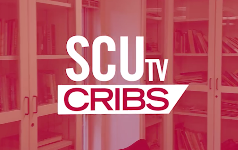 An SCUtv Cribs logo on a red transparent screen in front of book shelves with glass doors on the outside