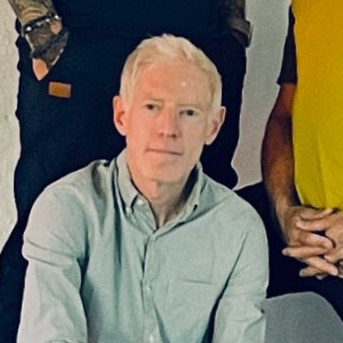 Brian Thorstensen seated in front of two people standing behind him.