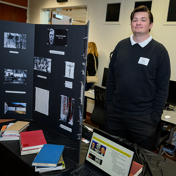 Joseph Barton '26 standing next t his display on Dietrich Bonhoeffer