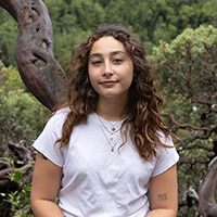Julia von Gersdorff standing next to a tree with green foliage in the background