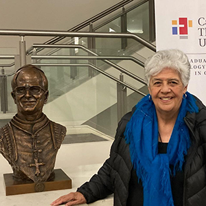 Ana Maria Pineda, RSM at Catholic Theological Union standing next to a stature of Pope Leo.
